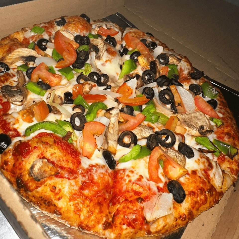 A BWP Pizza Island veggie pizza with tomatoes, olives, mushrooms, onions, and green peppers.