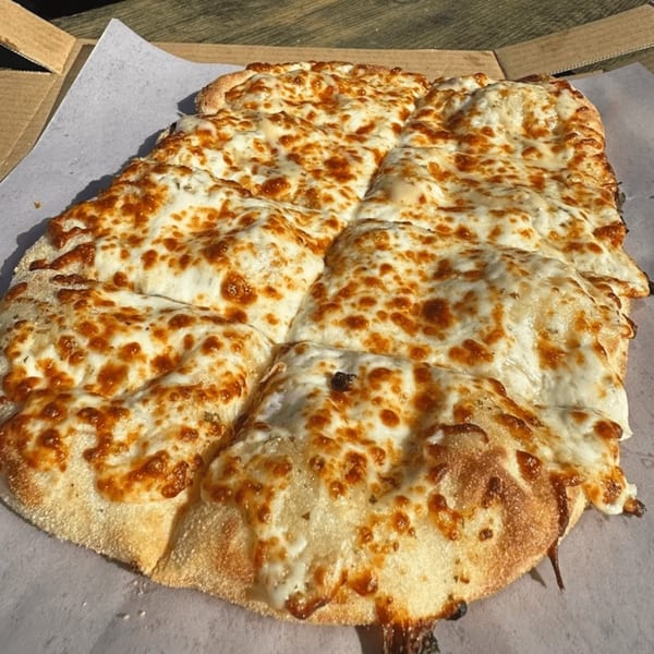 A rectangular cheese pizza, cut into squares, sits in a pizza box.